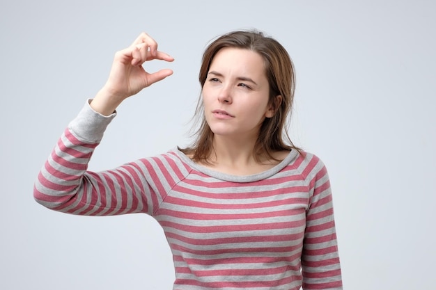 Mujer mostrando algo pequeño y diminuto con gesto