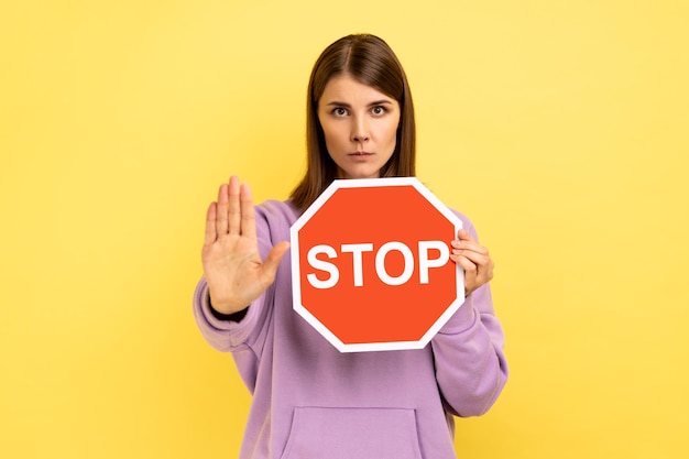 Mujer mostrando gesto de parada y sosteniendo prohibiciones y restricciones de señales de tráfico de parada roja