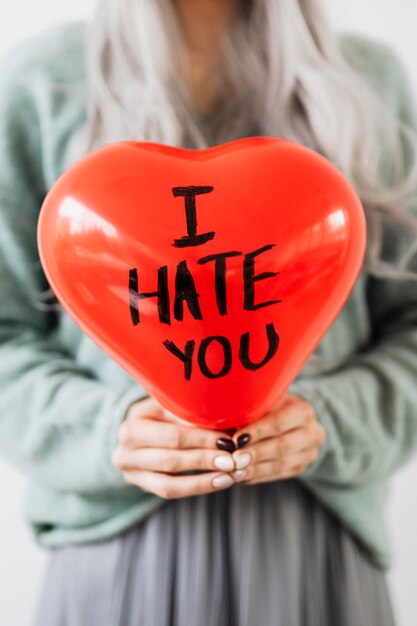 Mujer mostrando un globo de corazón rojo con te odio en él