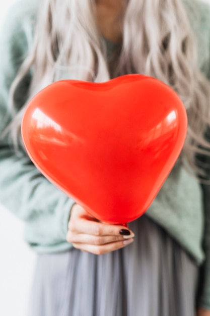 Mujer mostrando un globo rojo corazón