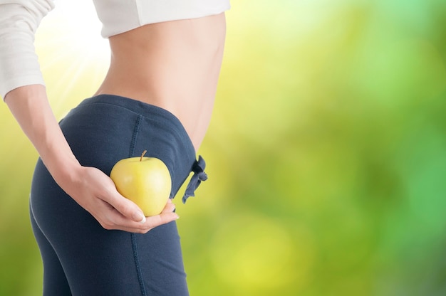 Mujer mostrando manzanas en cerca del vientre estómago