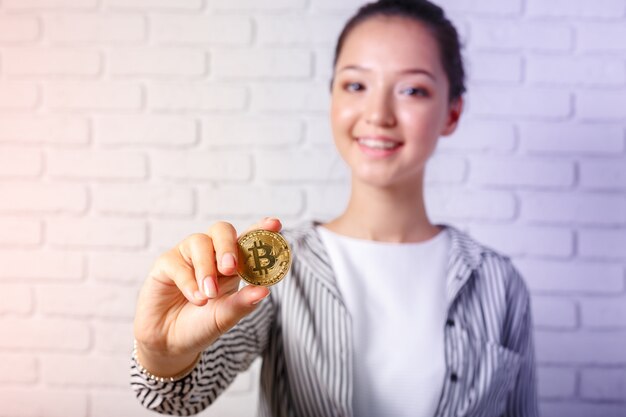 Mujer mostrando monedas de oro de Bitcoin