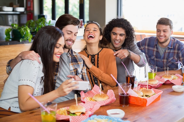 Foto mujer mostrando móvil a amigos alegres en el restaurante