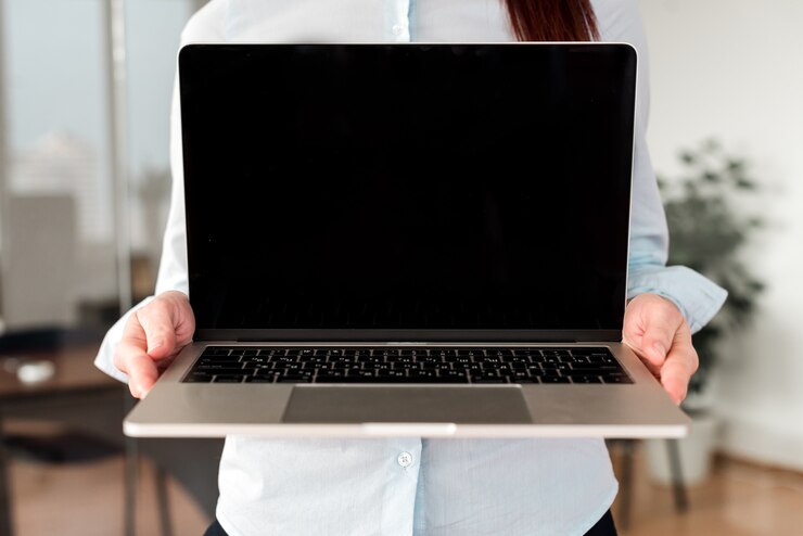 Foto mujer mostrando pantalla de portátil en blanco en la oficina