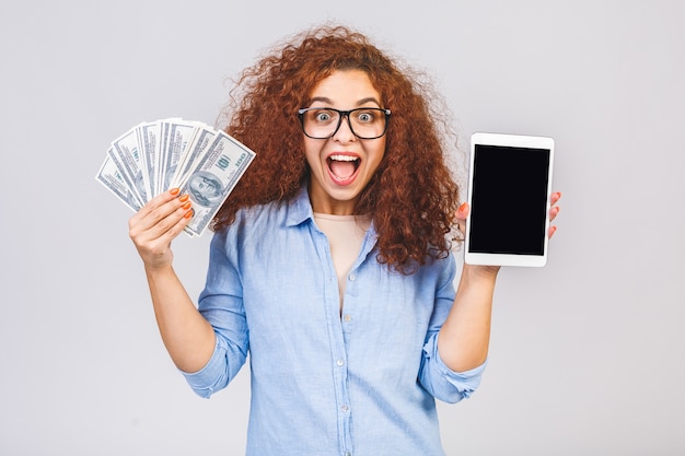 Mujer mostrando pantalla de tablet PC y sosteniendo dinero