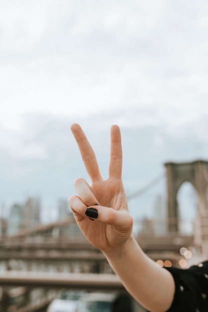 Mujer mostrando un signo V en el puente de Brooklyn, Estados Unidos