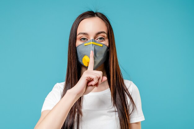 Mujer mostrando silencio con máscara de respirador