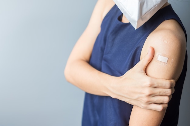 Mujer mostrando su brazo con vendaje después de recibir la vacuna covid 19. Vacunación, inmunidad colectiva, efectos secundarios, eficacia de la vacuna y pandemia de coronavirus