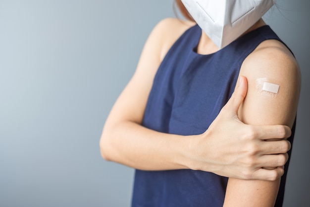 Mujer mostrando su brazo con vendaje después de recibir la vacuna covid 19