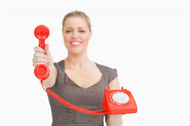 Mujer mostrando un teléfono retro rojo