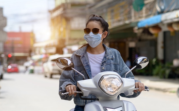 Mujer en motocicleta con una máscara en la ciudad