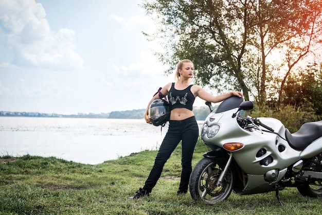 Mujer motociclista con descanso de motocicleta cerca de un estanque