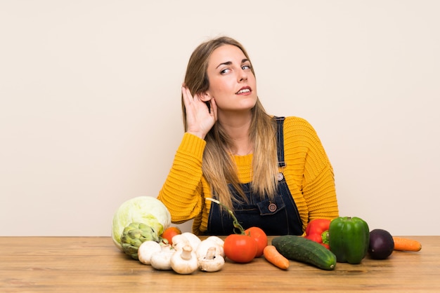 Foto mujer con muchas verduras escuchando algo