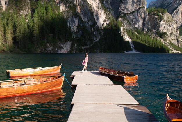 Mujer en el muelle con botes de madera en el lago de montaña en italia