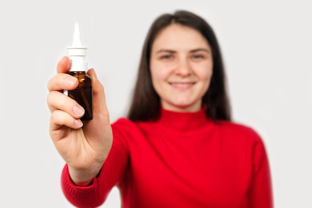 Una mujer muestra una botella de aerosol nasal para tratar la rinitis y las alergias.