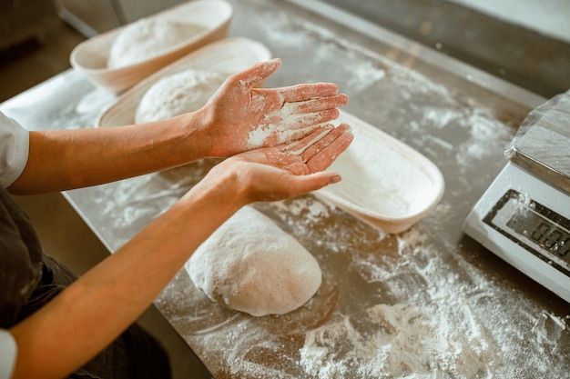 Mujer muestra palmas cubiertas con harina en panadería artesanal contemporánea