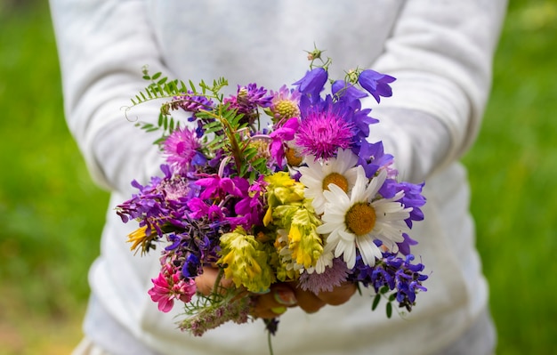 Mujer muestra un ramo de flores naturales con diferentes flores y colores - preocupación por la naturaleza y el medio ambiente - personas y margaritas para el estilo de vida del concepto de libertad y felicidad