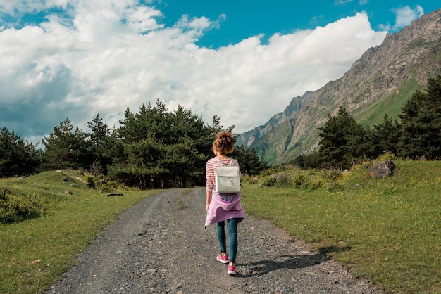 Mujer mujer feliz viajero caminando en campo con cielo azul en el paisaje