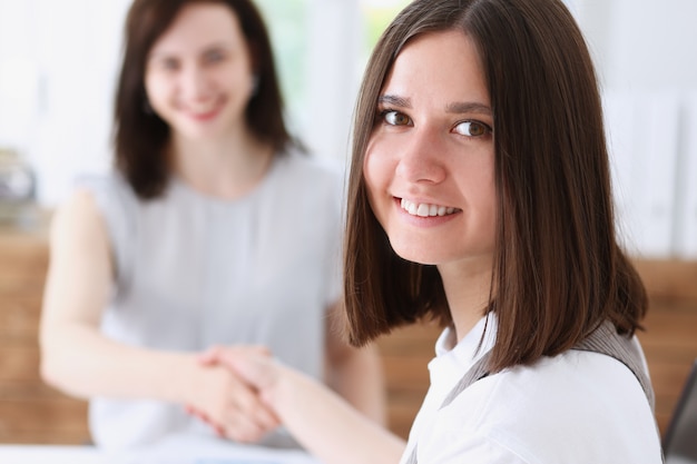 Mujer y mujer de negocios se dan la mano como