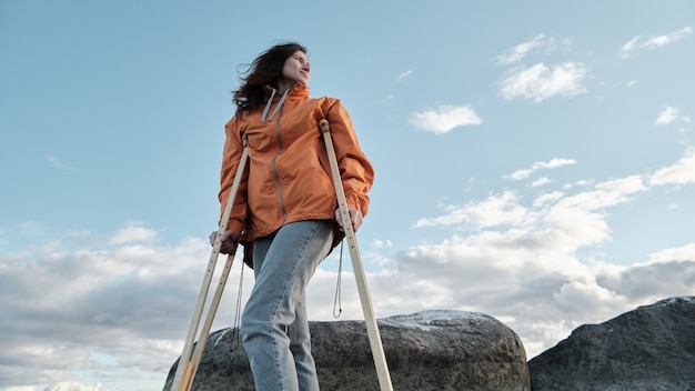 Una mujer con muletas camina por la orilla del lago.