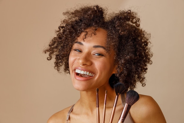 Mujer multirracial alegre posando en la cámara sobre fondo beige