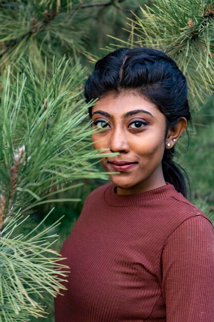 Foto una mujer multirracial en un parque posando modelo de piel morena natural cerca de un árbol linda sonrisa india mirando de lado en un árbol