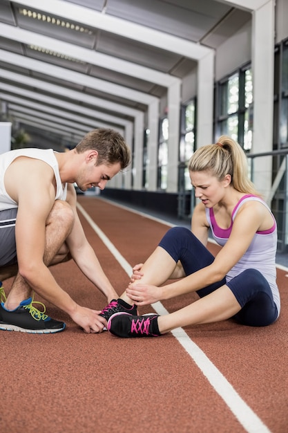 Mujer muscular que tiene una lesión de tobillo en el gimnasio de crossfit