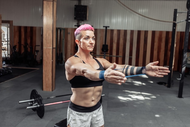 Una mujer musculosa y poderosa se ejercita con bandas elásticas de fitness en el gimnasio. Concepto de estilo de vida saludable