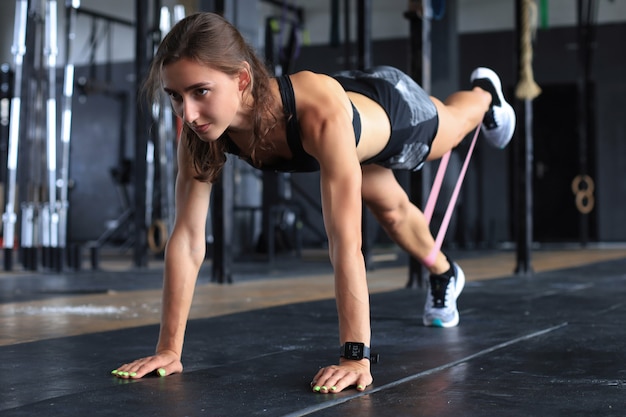 Foto mujer musculosa en posición de plancha utiliza goma de mascar.