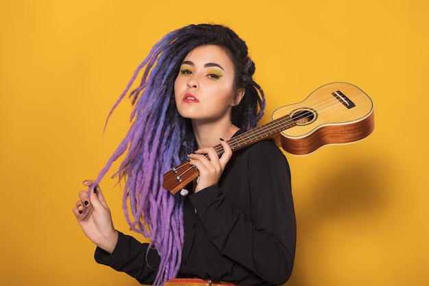 Foto mujer músico hipster feliz con ukelele dama con rastas moradas toca la guitarra hawaiana