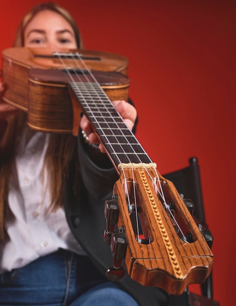 Mujer músico latinoamericana tocando un instrumento folclórico venezolano cuatro