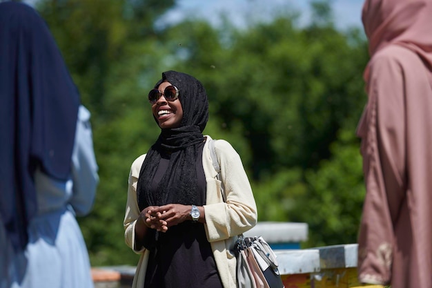 mujer musulmana africana negra dando una presentación a un grupo de inversores comerciales o turistas en una pequeña granja local de producción de miel