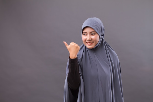 Mujer musulmana apuntando con el pulgar hacia arriba al espacio en blanco