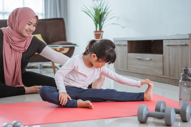 Mujer musulmana asiática e hija haciendo ejercicio y deporte en casa durante el autoaislamiento