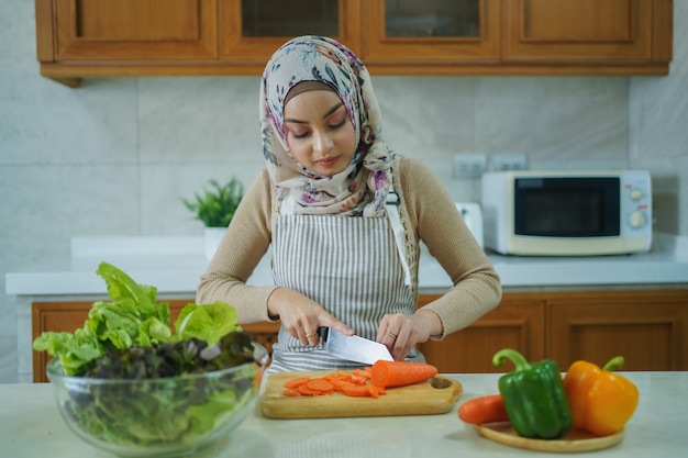 La mujer musulmana asiática está preparando las verduras para cocinar. Concepto de cocina en casa.