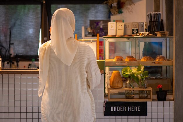 Mujer musulmana asiática de pie en el Café Bar pidiendo comida