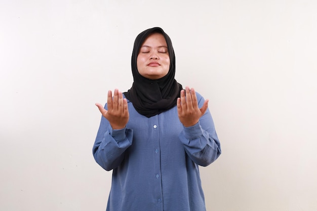 Foto mujer musulmana asiática de pie con un gesto de oración mientras cierra los ojos