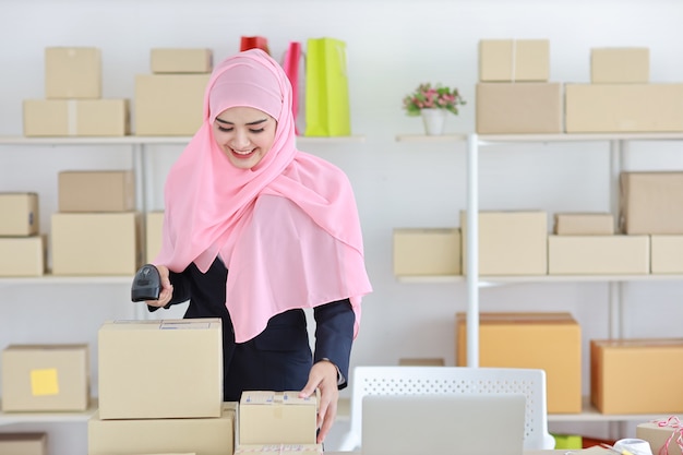 Mujer musulmana asiática de pie y sosteniendo el escáner con entrega de caja de paquete.
