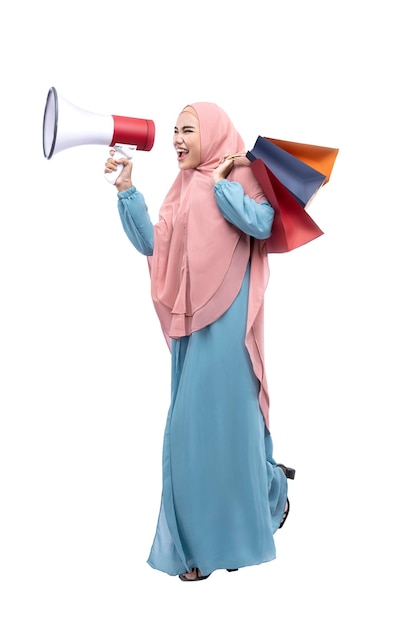 Mujer musulmana asiática con velo sosteniendo megáfono y bolsas de compras