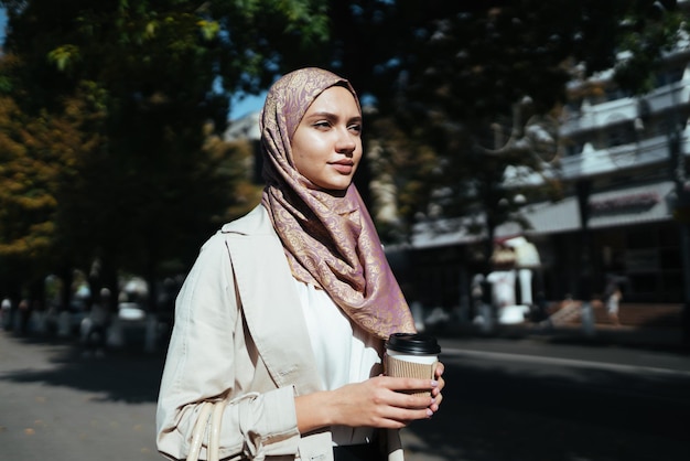 Mujer musulmana en el centro de la ciudad con café