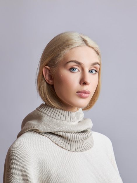 Mujer musulmana europea con el pelo rubio en un capot con capucha vestida sobre su cabeza. Hermosa chica en suéter con piel suave, cosmética natural