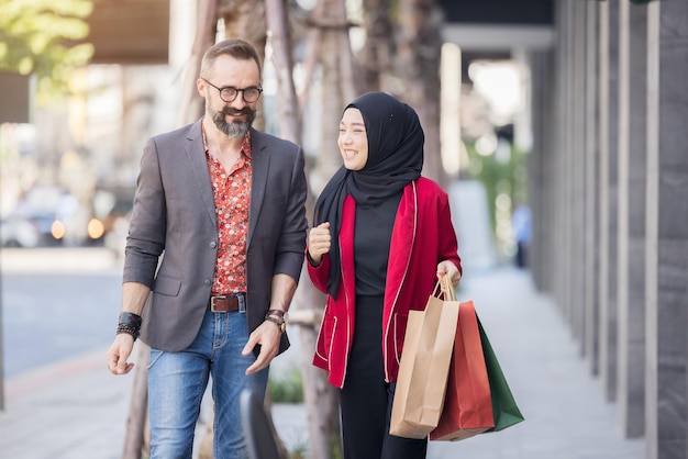 Foto mujer musulmana feliz y amigo de niño con la mano de compras de la ciudad sosteniendo bolsas de papel