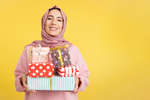 Mujer musulmana feliz con bufanda con muchos regalos