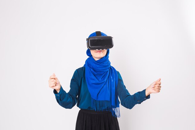 Mujer musulmana con gafas de realidad virtual. Foto de estudio, fondo blanco.