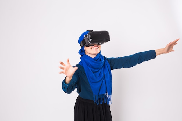 Mujer musulmana con gafas de realidad virtual. Foto de estudio, fondo blanco.