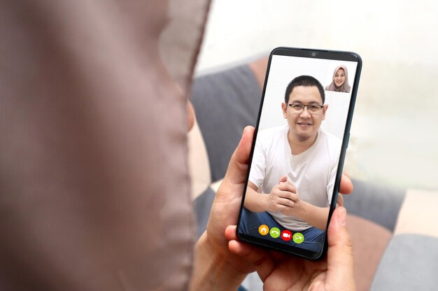 Foto mujer musulmana haciendo una videollamada con su hombre en un teléfono inteligente