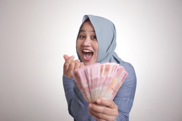 Mujer musulmana indonesia sosteniendo dinero en rupias