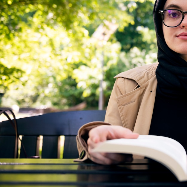 Mujer musulmana leyendo un libro en el parque durante su tiempo libre