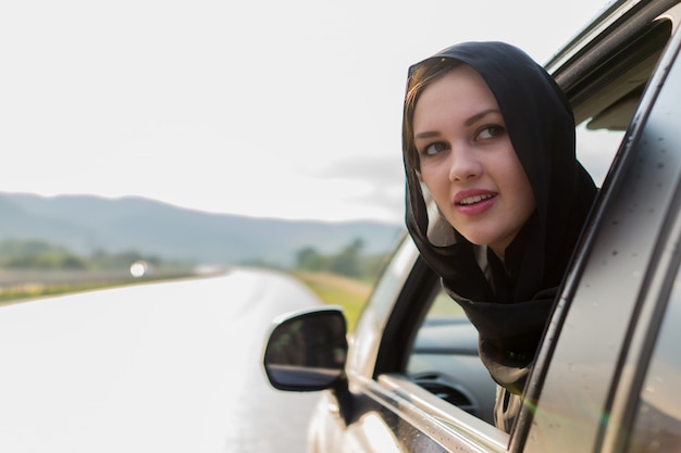 mujer musulmana mirando fuera de la ventana del coche