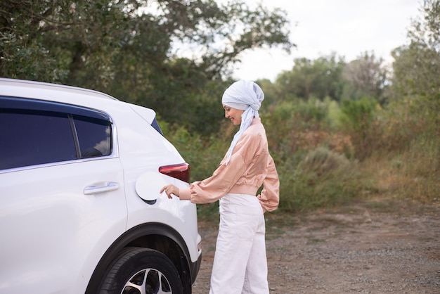 Una mujer musulmana moderna está cerrando la cubierta de benzo de su coche